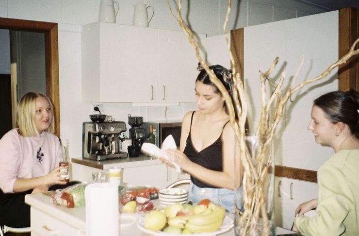 three people gathered around a kitchen island, preparing food